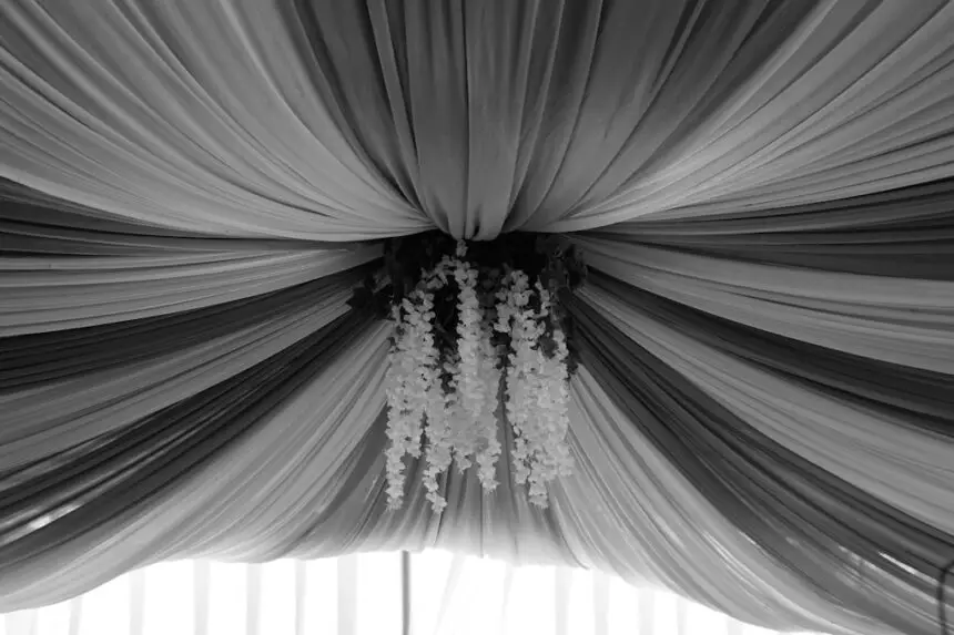 a black and white photo of a drape with flowers hanging from it