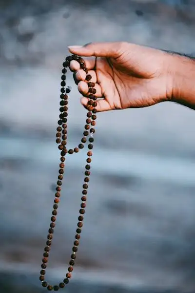 Close-up of a hand holding a Rudraksha bead necklace, symbolizing spirituality and meditation.