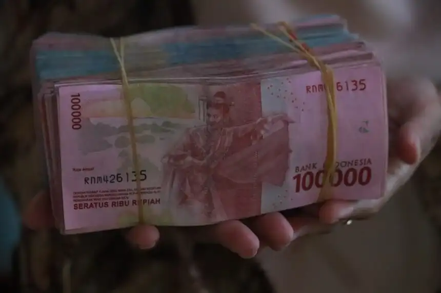 Person holding Indonesian rupiah representing personal finance and money management